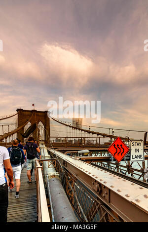 Brooklyn Bridge, New York, United States - June 08, 2015: People walk and  while other tourists observe, from the bridge, the Manhattan skyline. Stock Photo