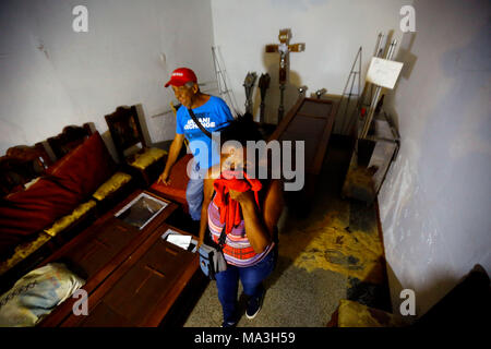 29 March 2018, Venezuela, Valencia: Mirian Rosa Oliveros (R) tries to find her relatives between numerous coffins after a mutiny in a police station. At least 68 people died. According to local sources the mutiny began when the prisoners tried to take their guard as a hostage. The prisoners burned mattresses, which got out of control and led to the numerous deaths. Photo: Juan Carlos Hernandez/dpa Stock Photo