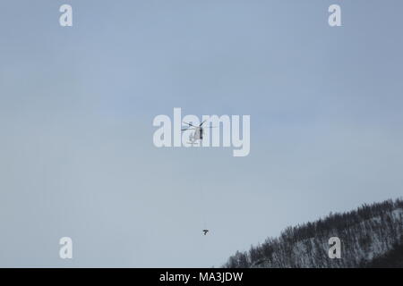 Rescue helicopter from UNN (University Hospital North Norway) rescues a skier who was taken in avalanhce, just outside Tromsø Norway.The heavy snow made them make more attempts to reach the victim. Due to the large snow crowds that have come across northern Norway in the last days, the danger of avalanching is at grade 4. (high) And there have been more natural triggered avalanches and avalanches triggered by skiers and snowmobiles in recent days.The authorities recommend people to stay away from areas with steep terrain. Stock Photo