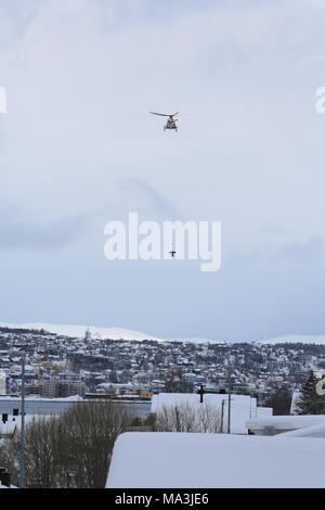 Rescue helicopter from UNN (University Hospital North Norway) rescues a skier who was taken in avalanhce, just outside Tromsø Norway.The heavy snow made them make more attempts to reach the victim. Due to the large snow crowds that have come across northern Norway in the last days, the danger of avalanching is at grade 4. (high) And there have been more natural triggered avalanches and avalanches triggered by skiers and snowmobiles in recent days.The authorities recommend people to stay away from areas with steep terrain. Stock Photo