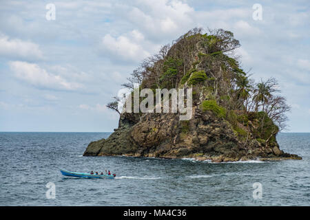 small island on ocean and people on small boat - Stock Photo