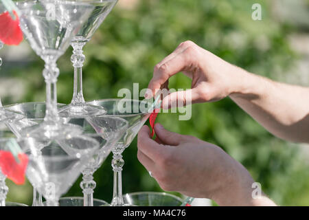 Hands of a waiter that makes out pyramid from glasses for drinks, wine, champagne, festive mood, celebration Stock Photo