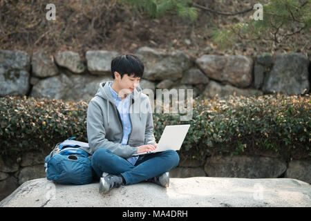 Asian man backpacking using laptop Stock Photo