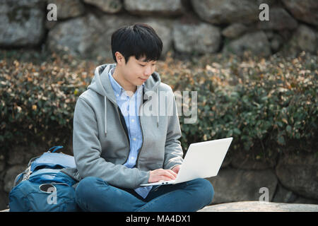 Asian man backpacking using laptop Stock Photo