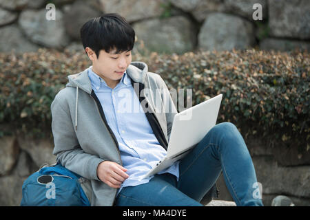 Asian man backpacking using laptop Stock Photo