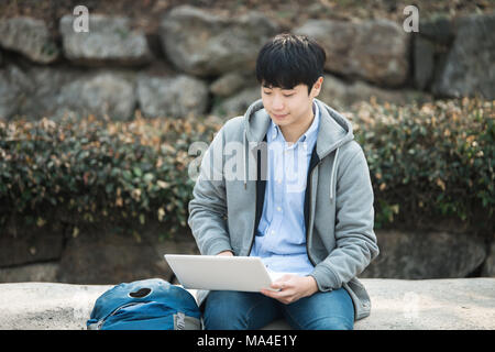 Asian man backpacking using laptop Stock Photo
