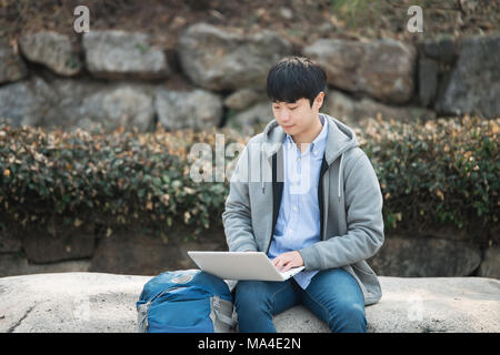 Asian man backpacking using laptop Stock Photo