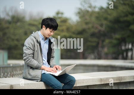 Asian man backpacking using laptop Stock Photo