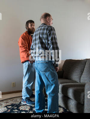 Two Caucasian men, 20s and an 80 year old senior, converse while the young man shows a surprised expression. Wichita, Kansas, USA. Stock Photo