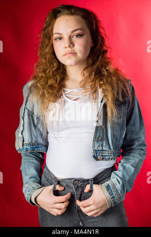 A moody attrractive young 13 thirteen year old teenage adolescent girl wearing a denim jacket, looking moody,  , UK Stock Photo