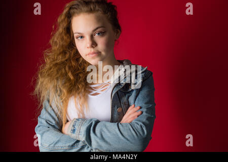 A moody attrractive young 13 thirteen year old teenage adolescent girl wearing a denim jacket, looking moody,  , UK Stock Photo