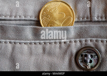 Euro coin with a denomination of 20 euro cents in the pocket of beige denim jeans with button Stock Photo