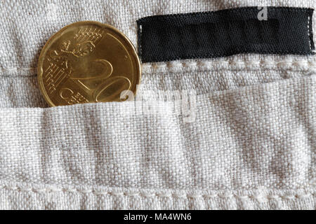 Euro coin with a denomination of 20 euro cents in the pocket of linen pants with black stripe Stock Photo