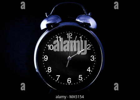 Old retro alarm clock with the hour and minute hands set to 2 o'clock 2 am or 2 pm isolated on a black background Stock Photo