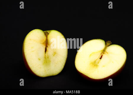 One red ripe apple sliced in half showing apple pips isolated on a black background Stock Photo