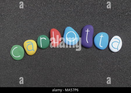 Carlotta, feminine given name with multicolored painted stones over black volcanic sand Stock Photo