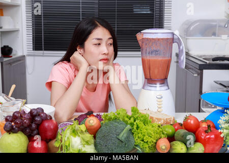 young woman making smoothies with blender in kitchen