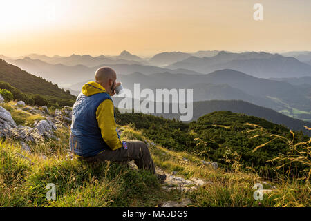 Germany, Bavaria, Bavarian foothills, Lenggries, hiker enjoys the morning mood with a coffee on the Benediktenwand (mountain) Stock Photo