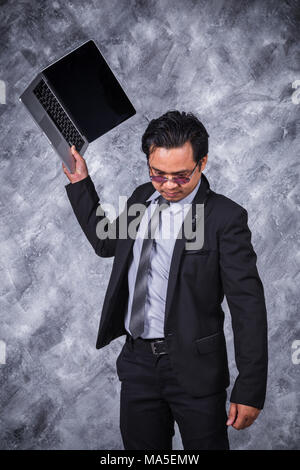 very angry business man is throwing away his laptop Stock Photo