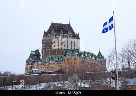 View of Frontenac Castel (Chateau de Frontenac, in French) in winter under the snow with a Quebec flag waiving. The Château Frontenac is a grand hotel Stock Photo