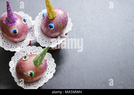 Easter cosmic purple and gold crafted eggs unicorns with eyes and colorful patterned horns on slate background with lace napkins. Copyspace. Top view Stock Photo