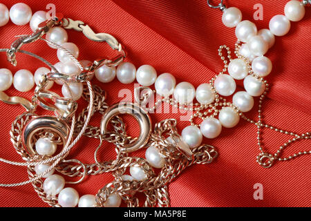 Pearl necklace and gold jewelry lying on red silk background with copy space  Stock Photo - Alamy