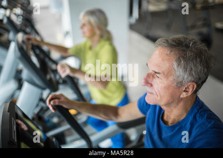 Profile portrait of senior man working out on stair stepper at gym Stock Photo