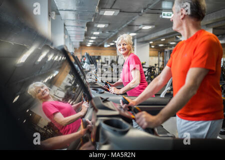 Portrait of happy senior lady training on treadmill with friend at gym Stock Photo