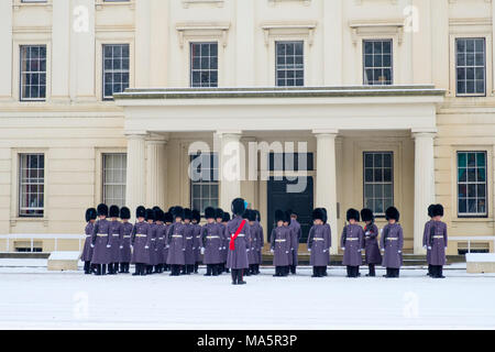 Irish guards from the Queens Guard regiments preparing for the Changing of the Guard ceremony with an inspection in the snow at Wellington Barracks Stock Photo