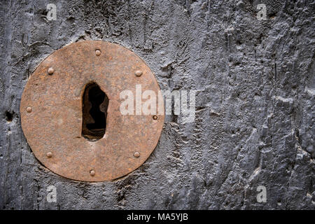 Rusty keyhole in old wooden door with steel nails, selective focus, copy space Stock Photo