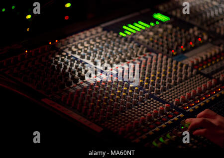 Mixing board with knows and green LED lights in a dark venue with narrow depth of field Stock Photo