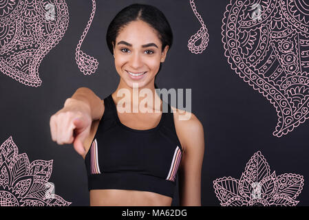Young cheerful woman pointing in front of herself and smiling Stock Photo