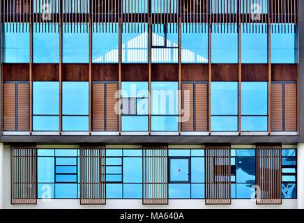 Front view of modern luxury house with blue glass windows and unique wooden cladding acting as sunshades and showing strong architectural elements Stock Photo