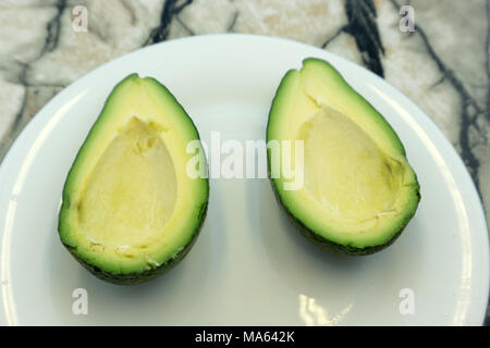 Sliced avocado top view isolated on white background ripe green brown alligator pear two halves with a seed Stock Photo