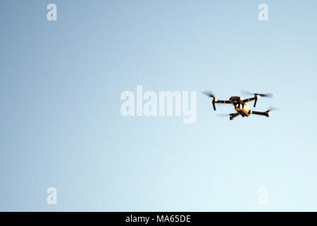 Drone flying overhead in cloudy blue sky Stock Photo
