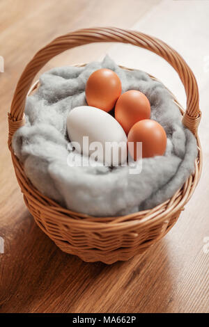 Goose egg and hens eggs, in a basket on fluffy wool. Stock Photo