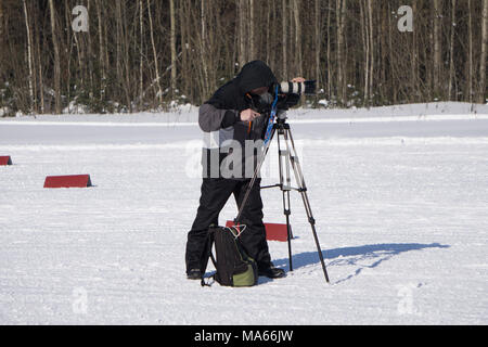 Professional video operator or videographer or cameraman standing with tripod and digital camera at blurred background of park with walking people, vi Stock Photo