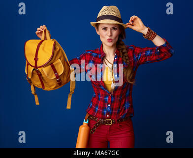 Searching for inspiring places. Portrait of smiling young traveller woman in a plaid shirt isolated on blue Stock Photo