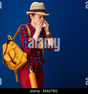 Searching for inspiring places. ill woman hiker in a plaid shirt blowing nose isolated on blue background Stock Photo