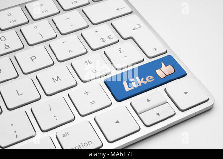 Like blue button with a thumb up icon on a white isolated keyboard. Social media, internet, web and business illustrative concept. Stock Photo