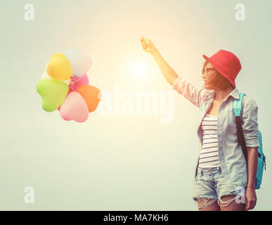 Teenage girls holding colorful balloons. carrying Blue backpack slung look very happy. Stock Photo