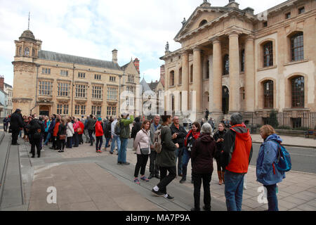 Groups of tourists being addressed by guides in front of The Clarendon Building and the Oxford Martin School, Oxford Stock Photo