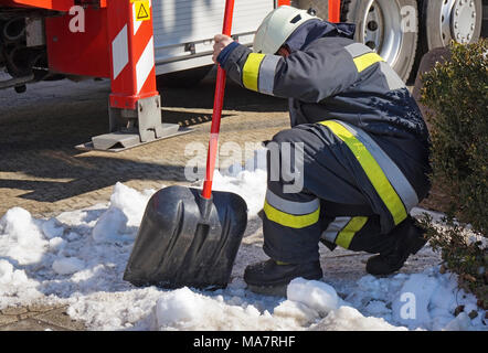 Firefighter works with a shovel in winter Stock Photo