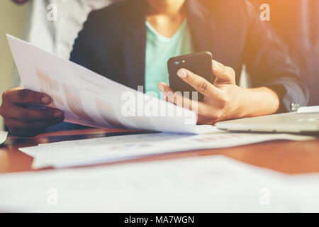 young man working using smartphone and notebook computer, Young man work and typing,financial work,workhard. Stock Photo