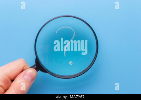 question mark under a magnifying glass with blue background Stock Photo