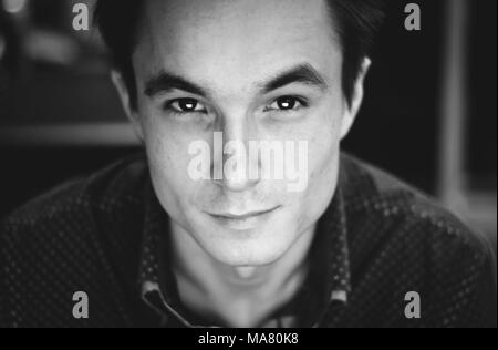 close-up portrait of a young cute guy in a shirt in an office setting, black and white image. Stock Photo