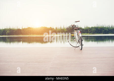Vintage toned of bicycle with basket on empty pier, summer day. Stock Photo