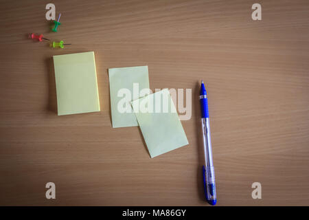 collection of pins and note paper bunch and loose papers on wooden board. ball point pen. top view ready to fill your text and design quotes Stock Photo