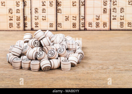 Pile of lotto kegs on the old wooden table with cards in the background Stock Photo