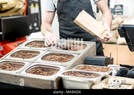 Filling paper bag with coffee beans from the metal tray for selling in the store Stock Photo